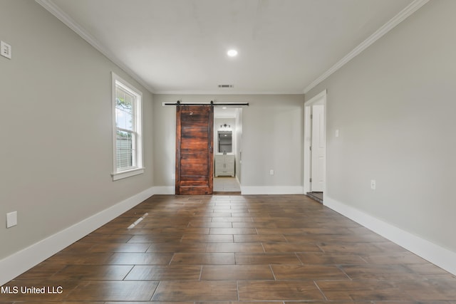 unfurnished room featuring a barn door, wood finished floors, visible vents, and baseboards