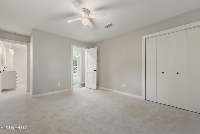 unfurnished bedroom with ceiling fan, light carpet, visible vents, baseboards, and a closet