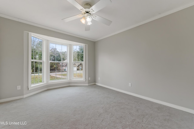 empty room with ceiling fan, ornamental molding, carpet flooring, and baseboards