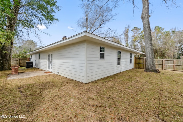 view of property exterior with central air condition unit, a fenced backyard, a patio, and a yard