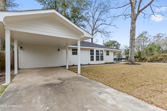 view of front facade with a carport, fence, concrete driveway, and a front yard