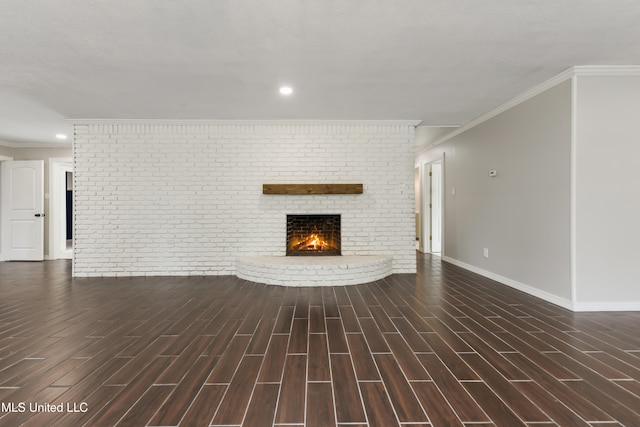 unfurnished living room featuring baseboards, brick wall, ornamental molding, wood finish floors, and a fireplace