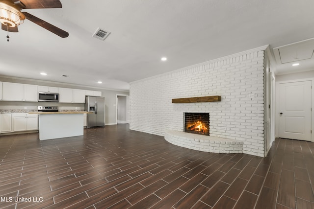 unfurnished living room with brick wall, a fireplace, visible vents, and wood tiled floor