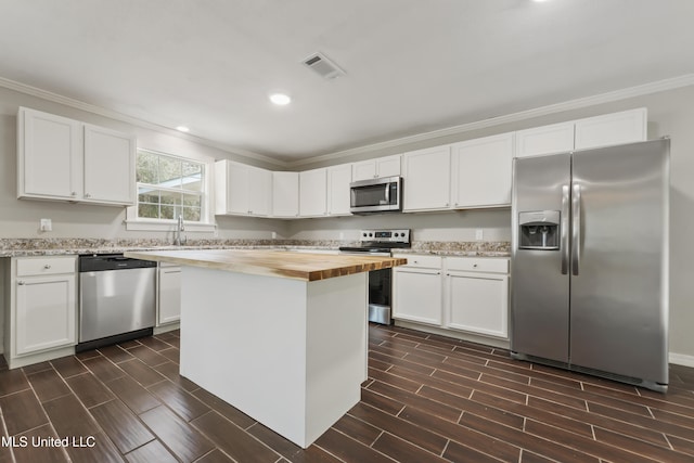 kitchen featuring visible vents, butcher block countertops, ornamental molding, wood tiled floor, and stainless steel appliances