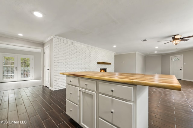 kitchen featuring french doors, crown molding, wood tiled floor, brick wall, and butcher block countertops