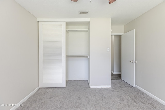 unfurnished bedroom with ceiling fan, light colored carpet, and a closet