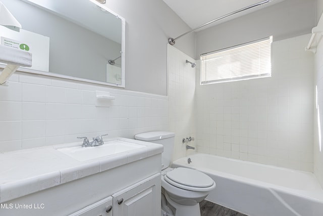 full bathroom featuring hardwood / wood-style floors, vanity, tiled shower / bath combo, toilet, and tile walls