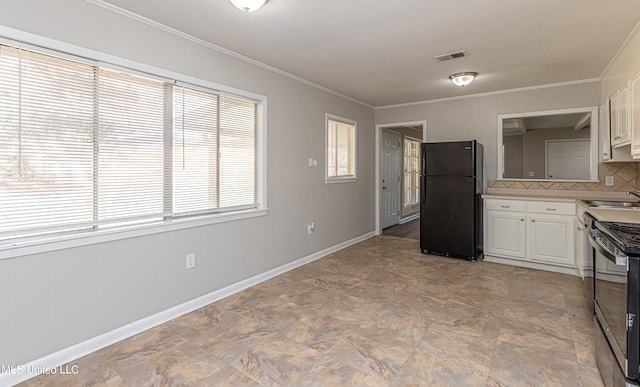 kitchen featuring black refrigerator, white cabinets, a healthy amount of sunlight, and stainless steel stove