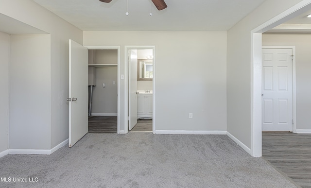 unfurnished bedroom with ensuite bathroom, ceiling fan, and light colored carpet