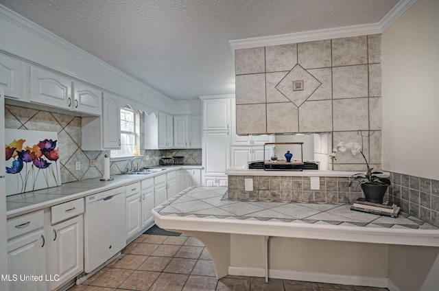 kitchen featuring sink, tasteful backsplash, tile counters, dishwasher, and white cabinets