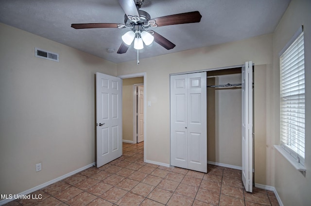 unfurnished bedroom featuring light tile patterned floors, a textured ceiling, ceiling fan, and a closet