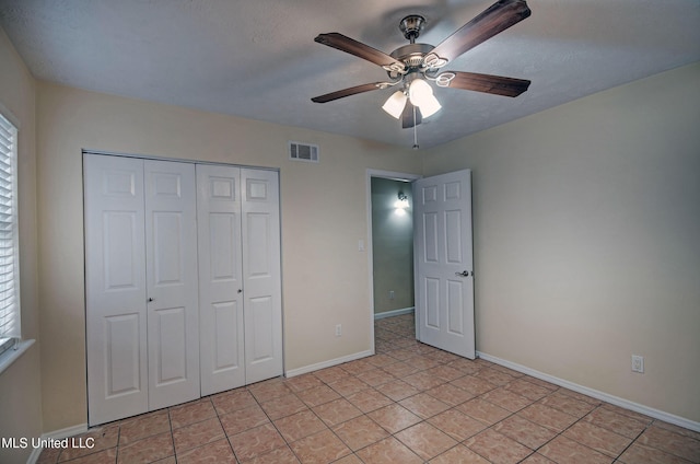 unfurnished bedroom with a textured ceiling, a closet, ceiling fan, and light tile patterned flooring