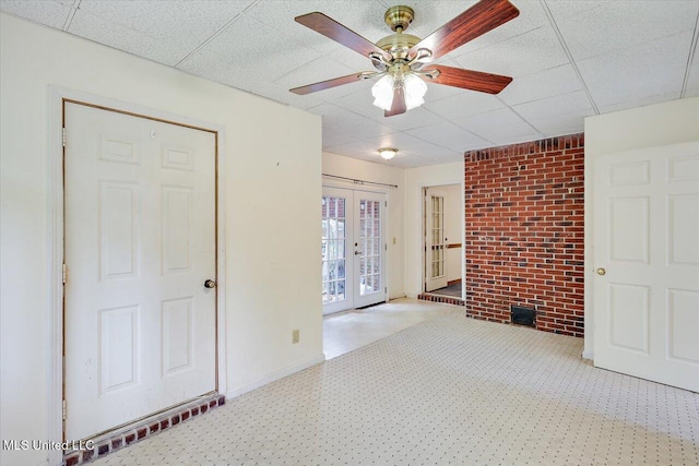 634 Twin Harbor Pl, Madison, MS 39110 - empty room with brick wall, a paneled ceiling, a ceiling fan, french doors, and baseboards