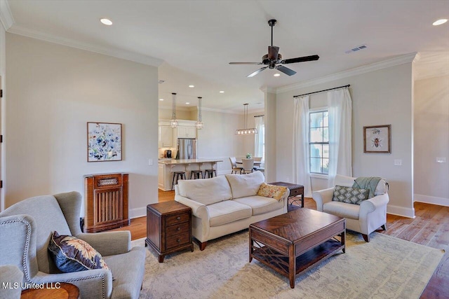 living room with ornamental molding, light hardwood / wood-style floors, and ceiling fan