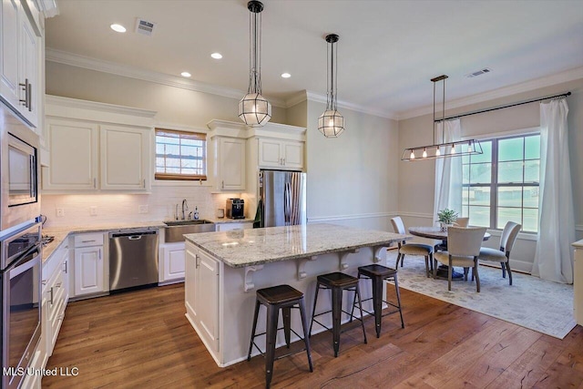 kitchen with sink, white cabinetry, appliances with stainless steel finishes, a kitchen island, and decorative backsplash