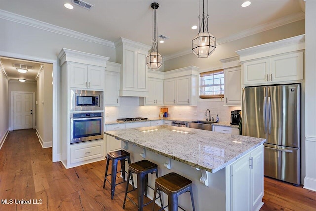 kitchen with stainless steel appliances, a center island, sink, and white cabinets