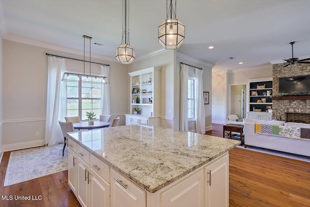 kitchen featuring white cabinetry, a center island, ornamental molding, pendant lighting, and hardwood / wood-style floors