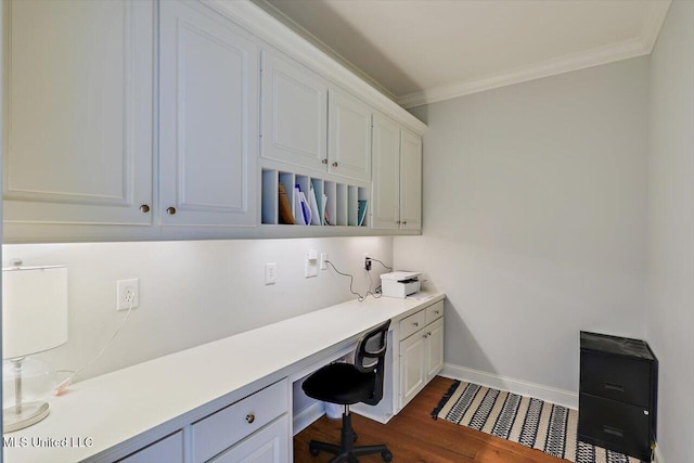 home office featuring dark wood-type flooring, ornamental molding, and built in desk