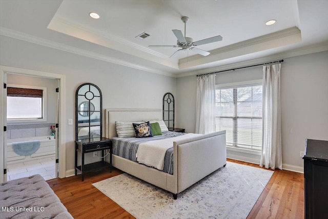 bedroom with crown molding, hardwood / wood-style flooring, and a raised ceiling