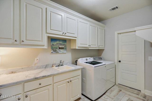 laundry area featuring cabinets, washer and clothes dryer, sink, and light wood-type flooring