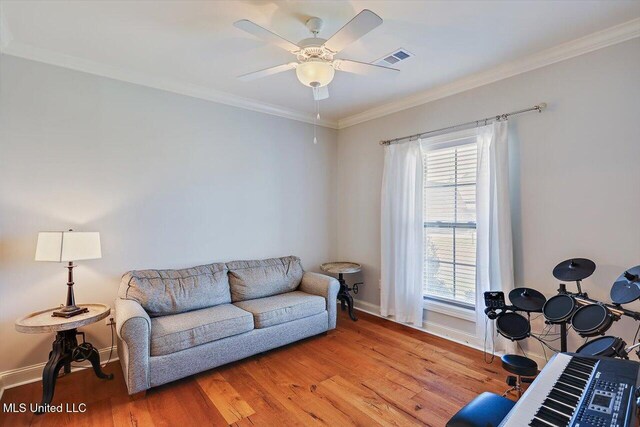 living room featuring ornamental molding, ceiling fan, and light wood-type flooring