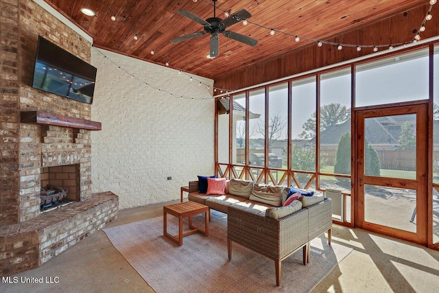 sunroom featuring ceiling fan, lofted ceiling, a stone fireplace, and wooden ceiling