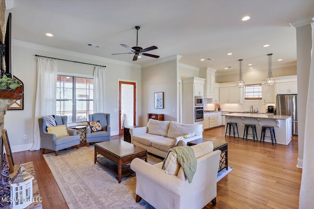 living room featuring ornamental molding, plenty of natural light, and light wood-type flooring