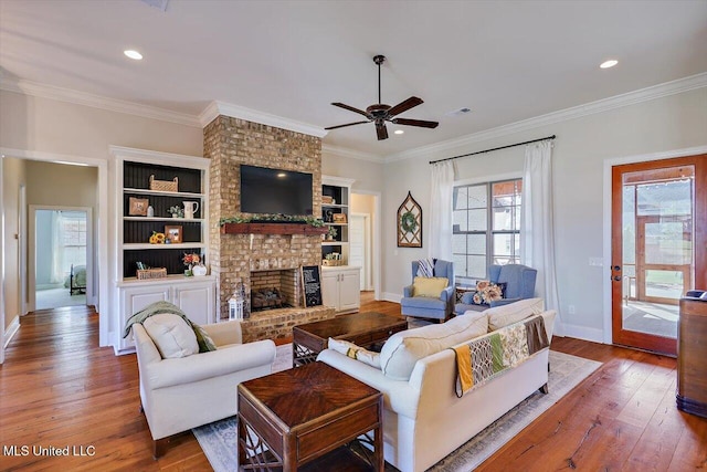 living room with hardwood / wood-style flooring, a fireplace, ornamental molding, and ceiling fan