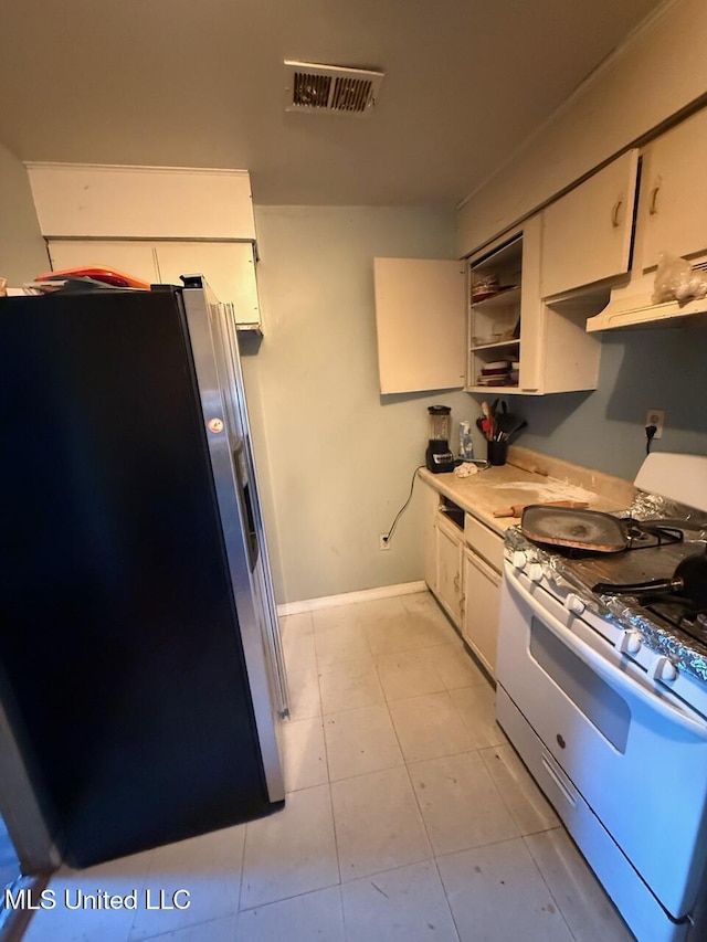 519 Copp St, Biloxi, MS 39530 - kitchen featuring visible vents, gas range gas stove, light countertops, stainless steel fridge with ice dispenser, and white cabinets