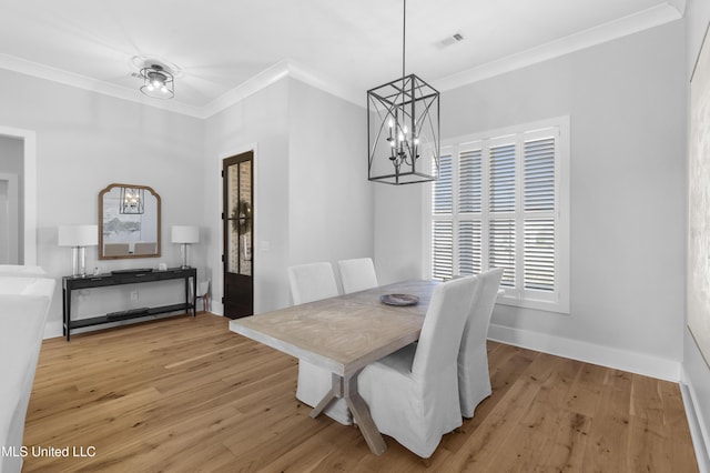 dining space featuring a notable chandelier, light hardwood / wood-style floors, and crown molding