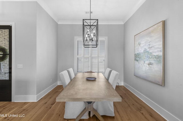 dining area featuring an inviting chandelier, light wood-type flooring, and ornamental molding