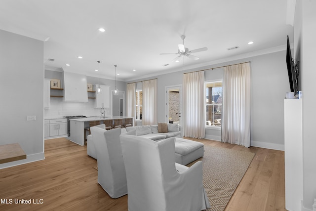 living room featuring light hardwood / wood-style floors, crown molding, and sink