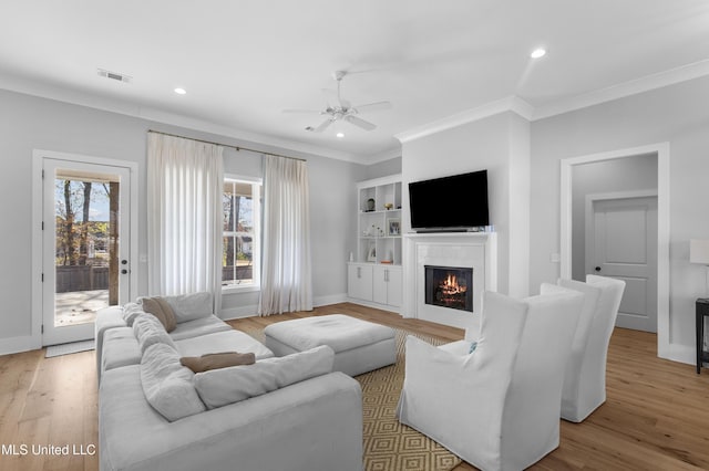 living room with ceiling fan, ornamental molding, and light hardwood / wood-style flooring