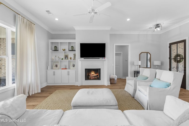 living room featuring light hardwood / wood-style floors, ceiling fan, and ornamental molding