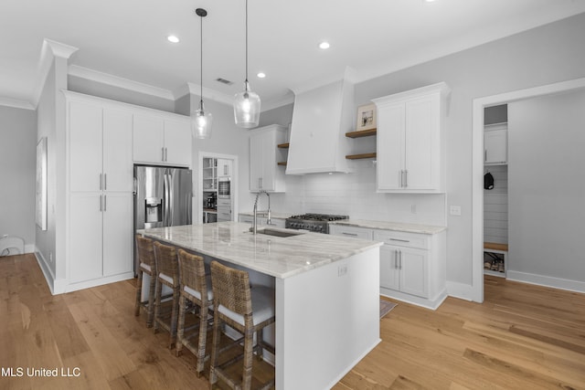 kitchen featuring white cabinetry, sink, an island with sink, and decorative light fixtures