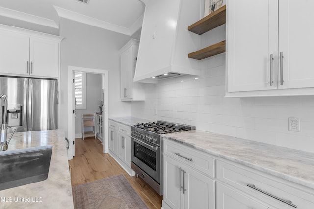 kitchen with white cabinetry, premium range hood, stainless steel appliances, and ornamental molding