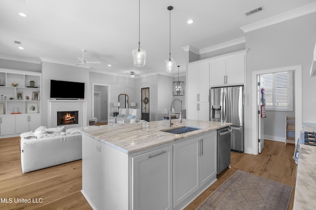 kitchen featuring sink, white cabinetry, stainless steel appliances, and an island with sink