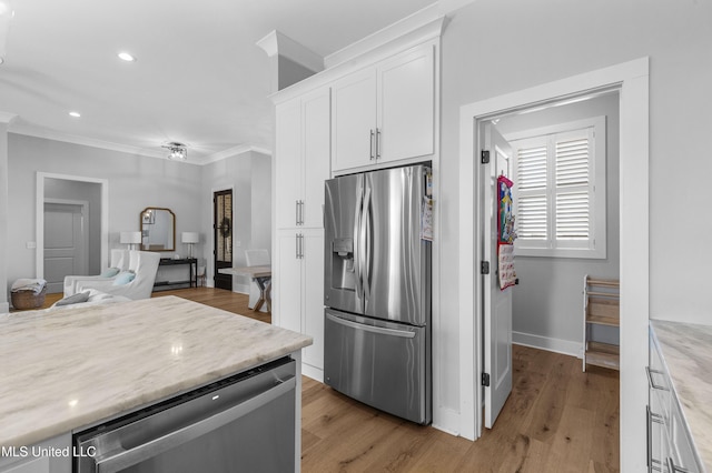 kitchen with appliances with stainless steel finishes, light wood-type flooring, white cabinetry, and crown molding