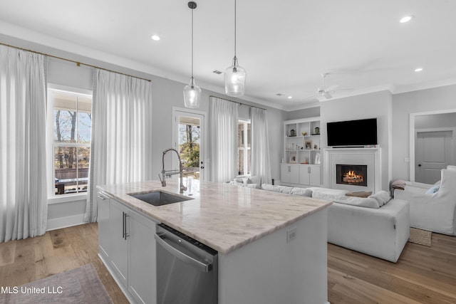 kitchen featuring sink, stainless steel dishwasher, decorative light fixtures, a kitchen island with sink, and white cabinets