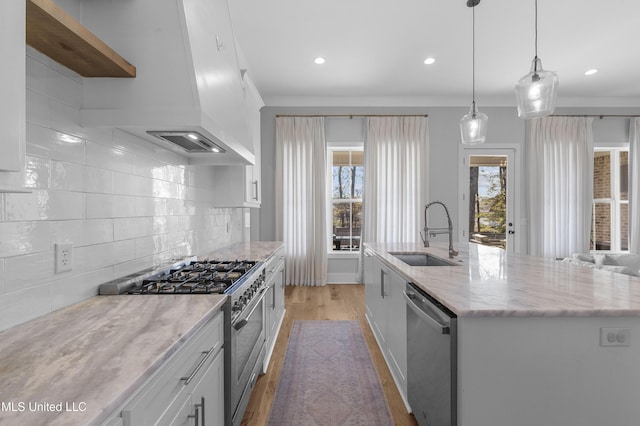 kitchen with white cabinets, sink, appliances with stainless steel finishes, and an island with sink