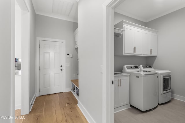 laundry room featuring washing machine and clothes dryer, light hardwood / wood-style floors, cabinets, and ornamental molding