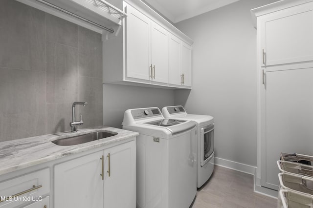 washroom featuring cabinets, washing machine and dryer, and sink