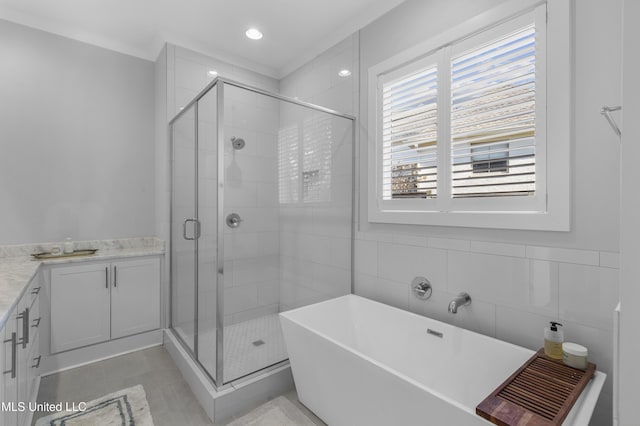 bathroom featuring vanity, plus walk in shower, tile patterned floors, ornamental molding, and tile walls