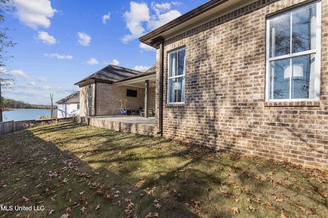 view of side of home with a lawn, a patio area, and a water view