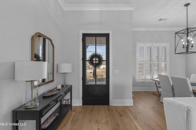 entrance foyer featuring light hardwood / wood-style floors, an inviting chandelier, and crown molding