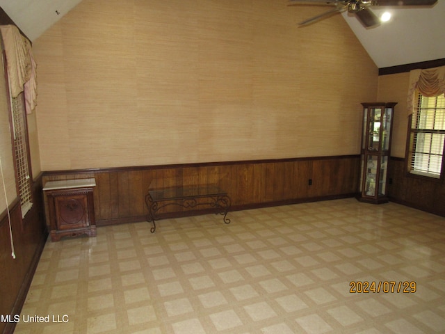 spare room featuring wooden walls, high vaulted ceiling, and ceiling fan