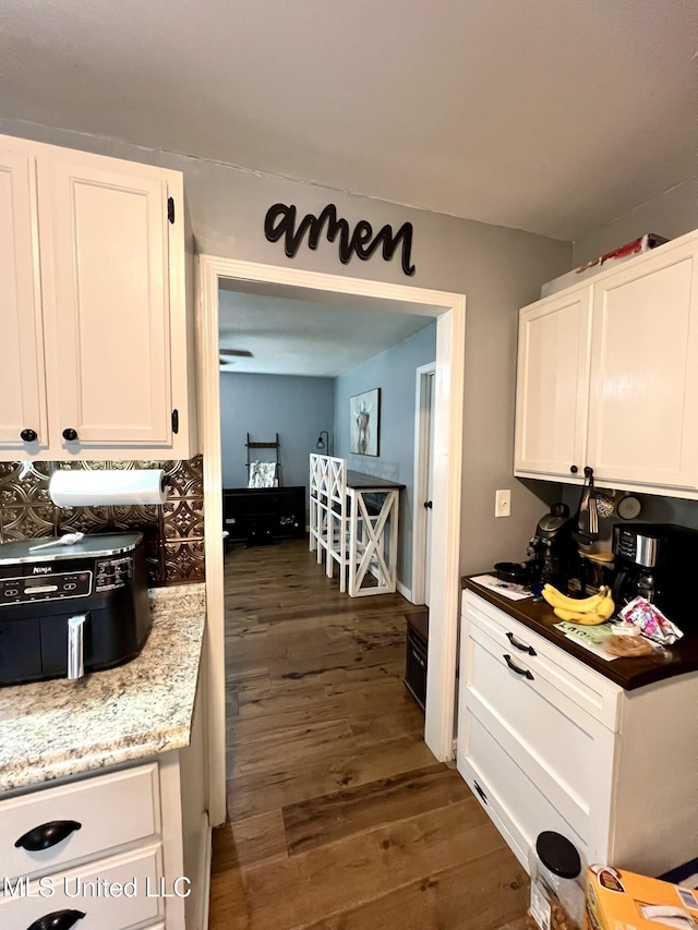 kitchen featuring light stone countertops, white cabinets, and dark wood-type flooring