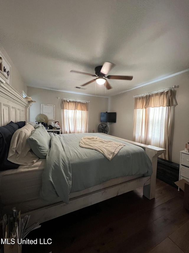 bedroom with visible vents, ceiling fan, and dark wood-style flooring