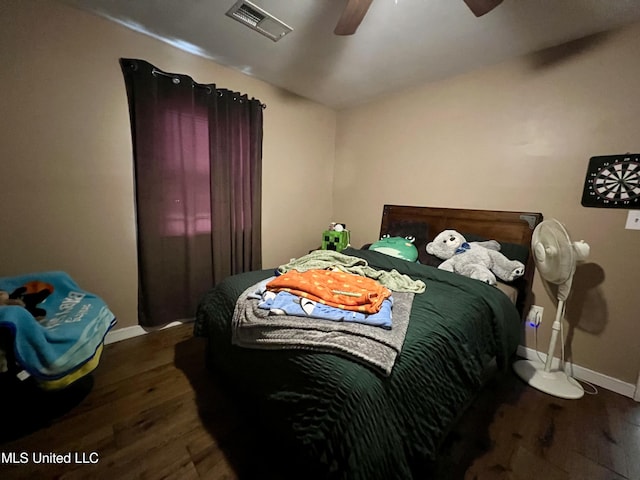bedroom with wood finished floors, a ceiling fan, visible vents, and baseboards