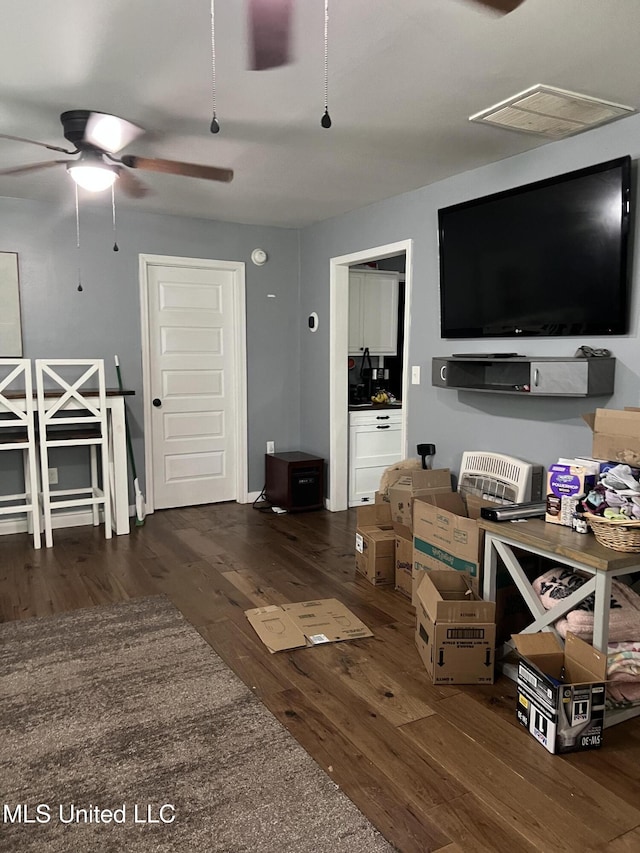 living area with visible vents, wood finished floors, and a ceiling fan